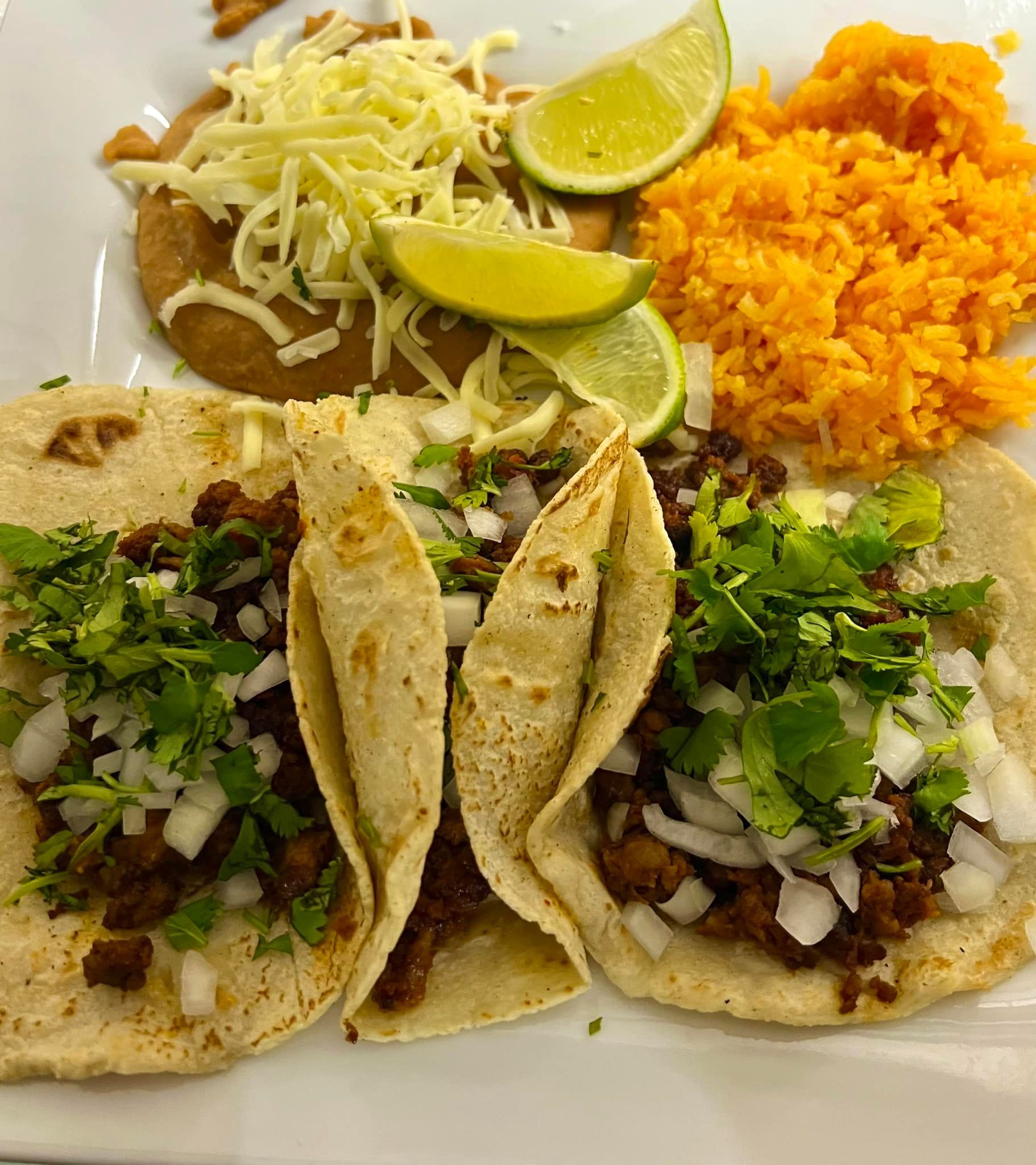 A white plate topped with tacos , rice and beans.