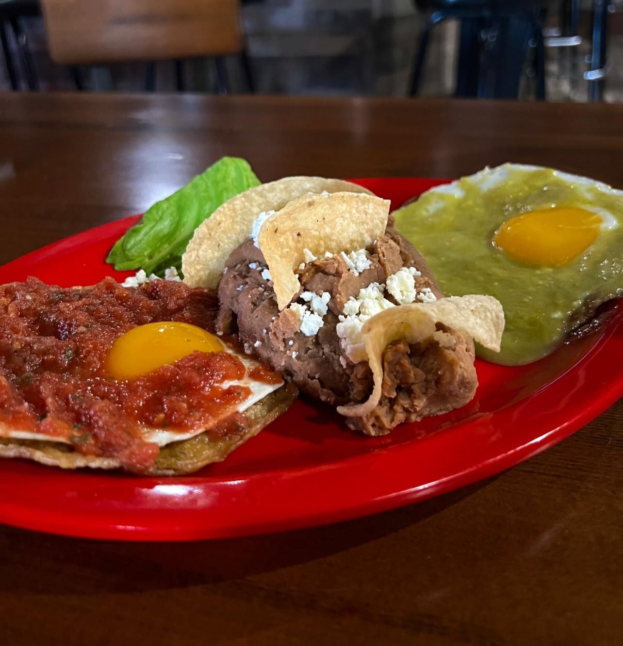 A red plate with a variety of mexican food on it