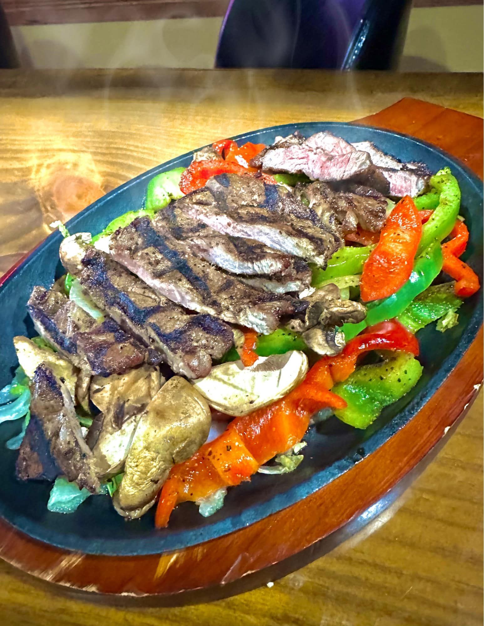 A plate of food with meat and vegetables on a wooden table.