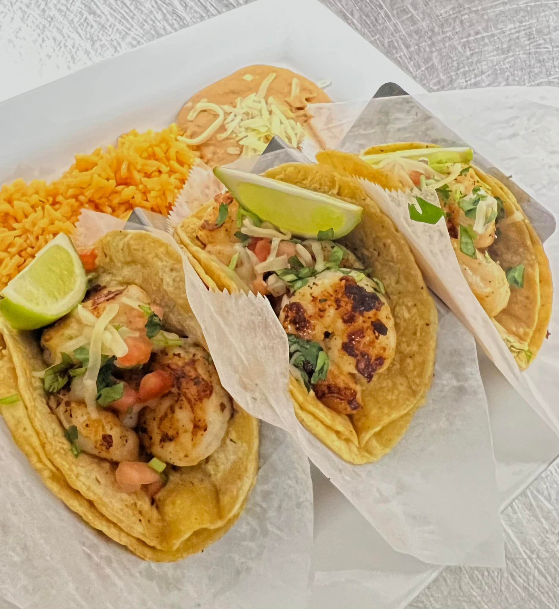 Three tacos with shrimp and rice on a plate