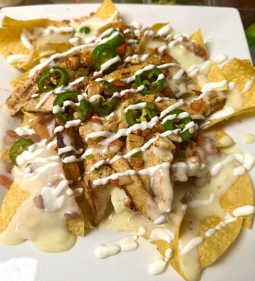 A close up of a plate of nachos with chicken and cheese