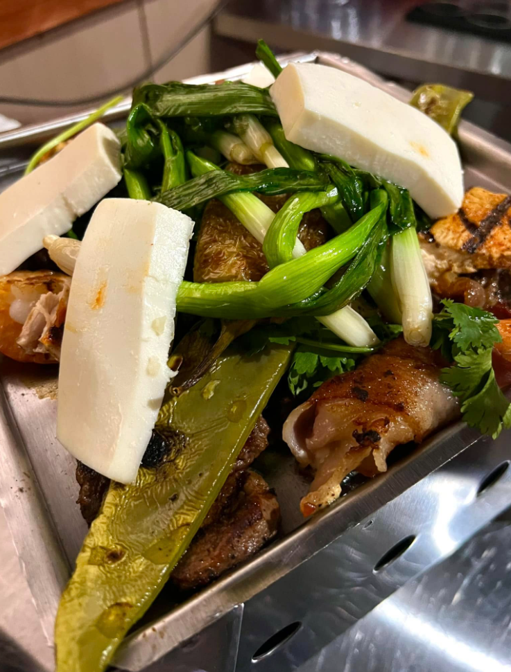 A close up of a plate of food with vegetables and cheese on a table.