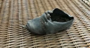 Old, worn leather shoe on a woven wicker surface.