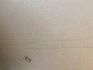 Water stain on a white ceiling, near a recessed light.