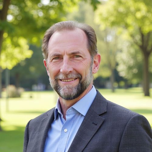 Portrait of a smiling man in a suit outdoors in a sunlit park