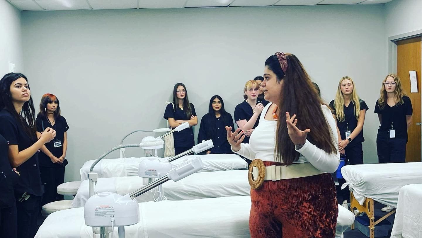 A woman is standing in front of a group of people in a room.