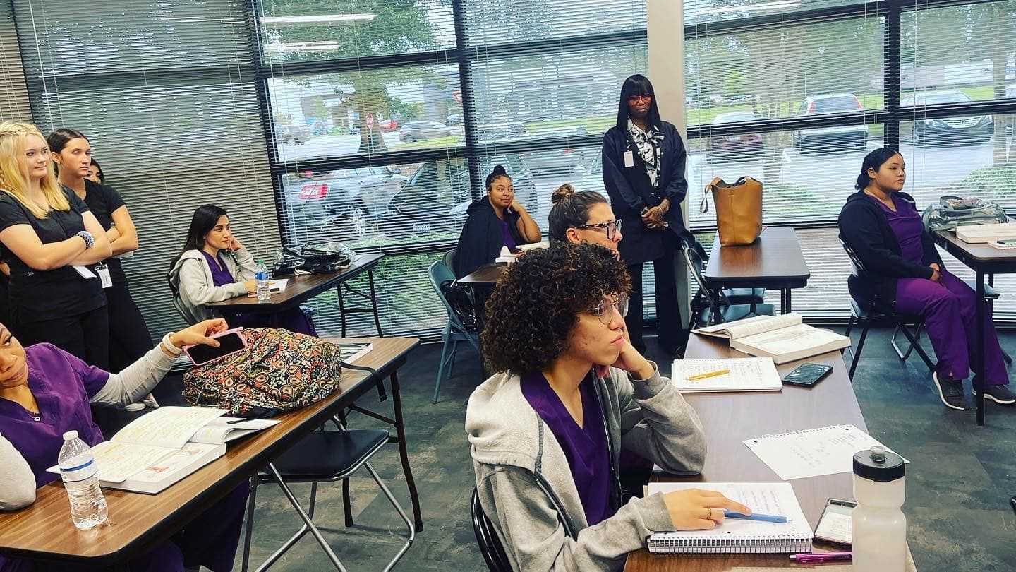 A group of women are sitting at tables in a classroom.