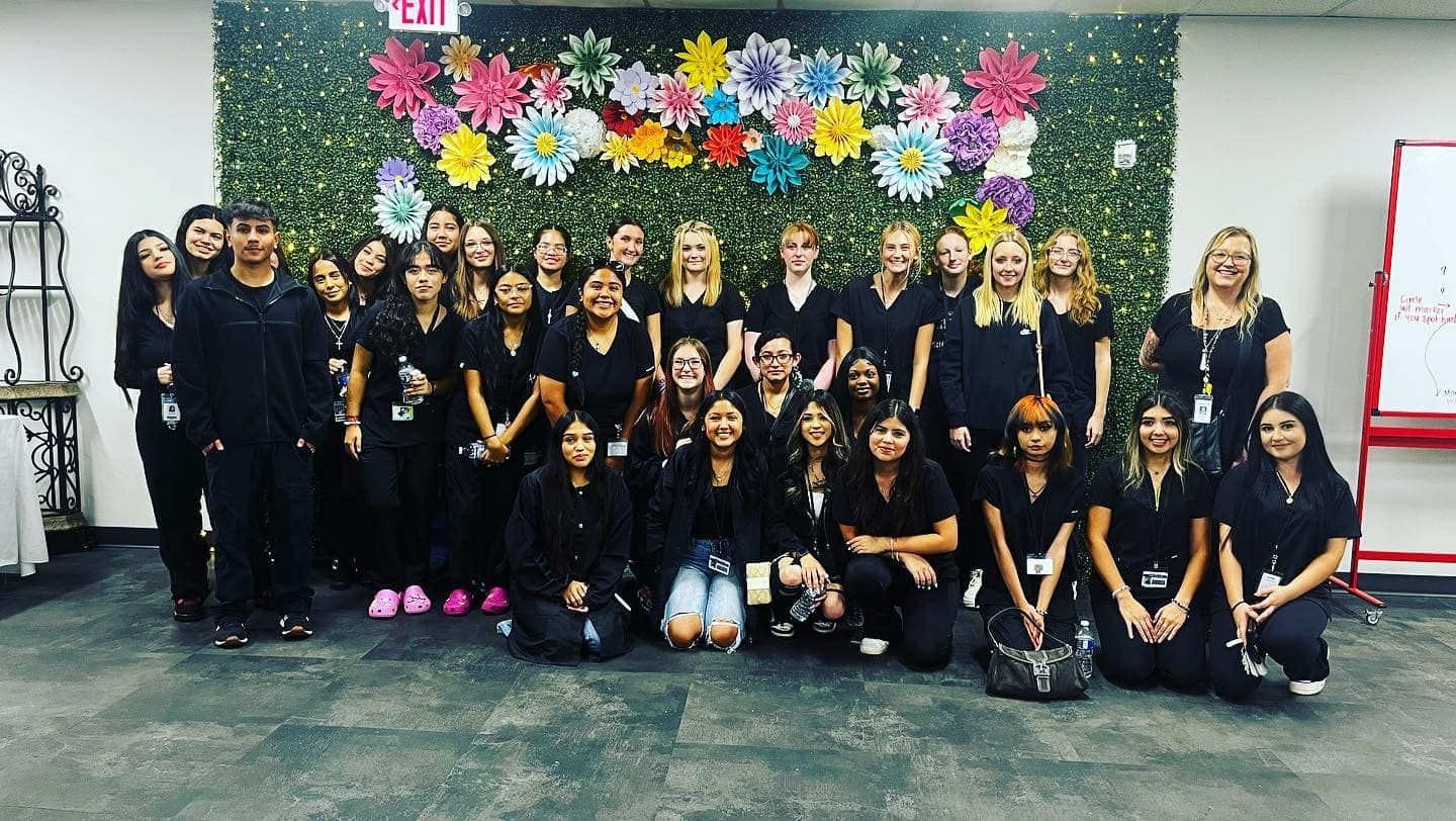 A group of people are posing for a picture in front of a wall with flowers.