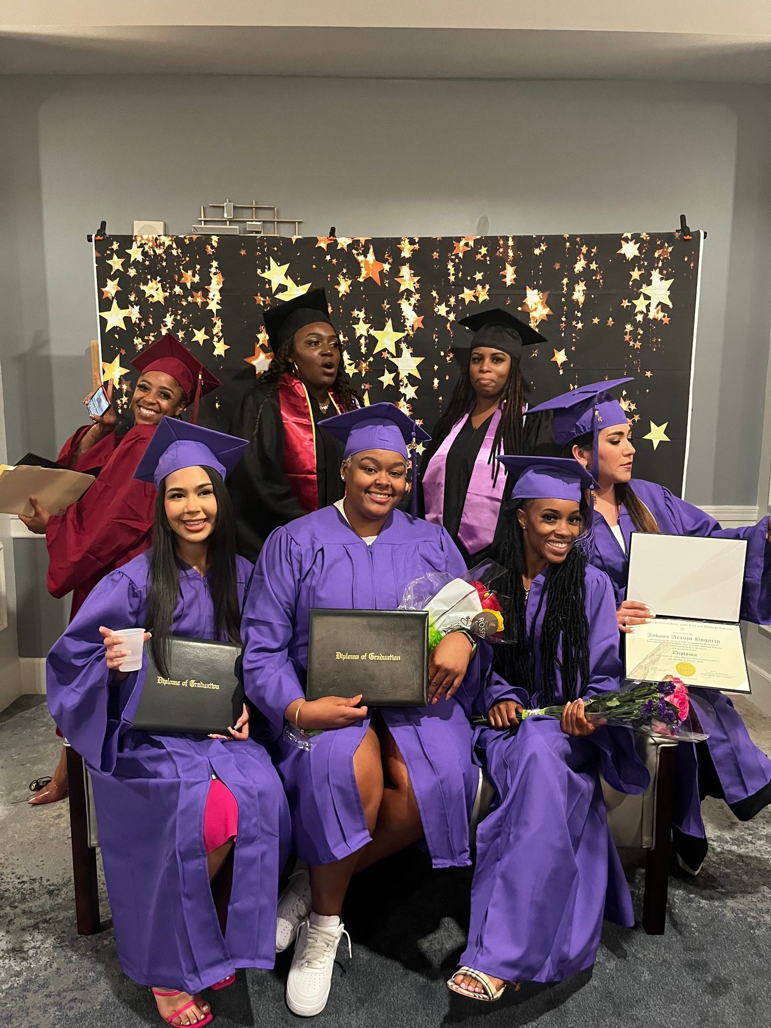 A group of women in purple graduation gowns and caps are posing for a picture.