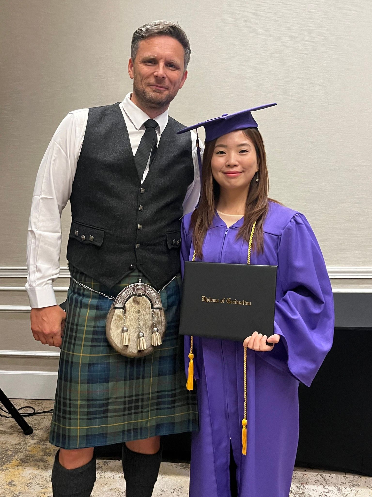 A man in a kilt is standing next to a woman in a graduation cap and gown.