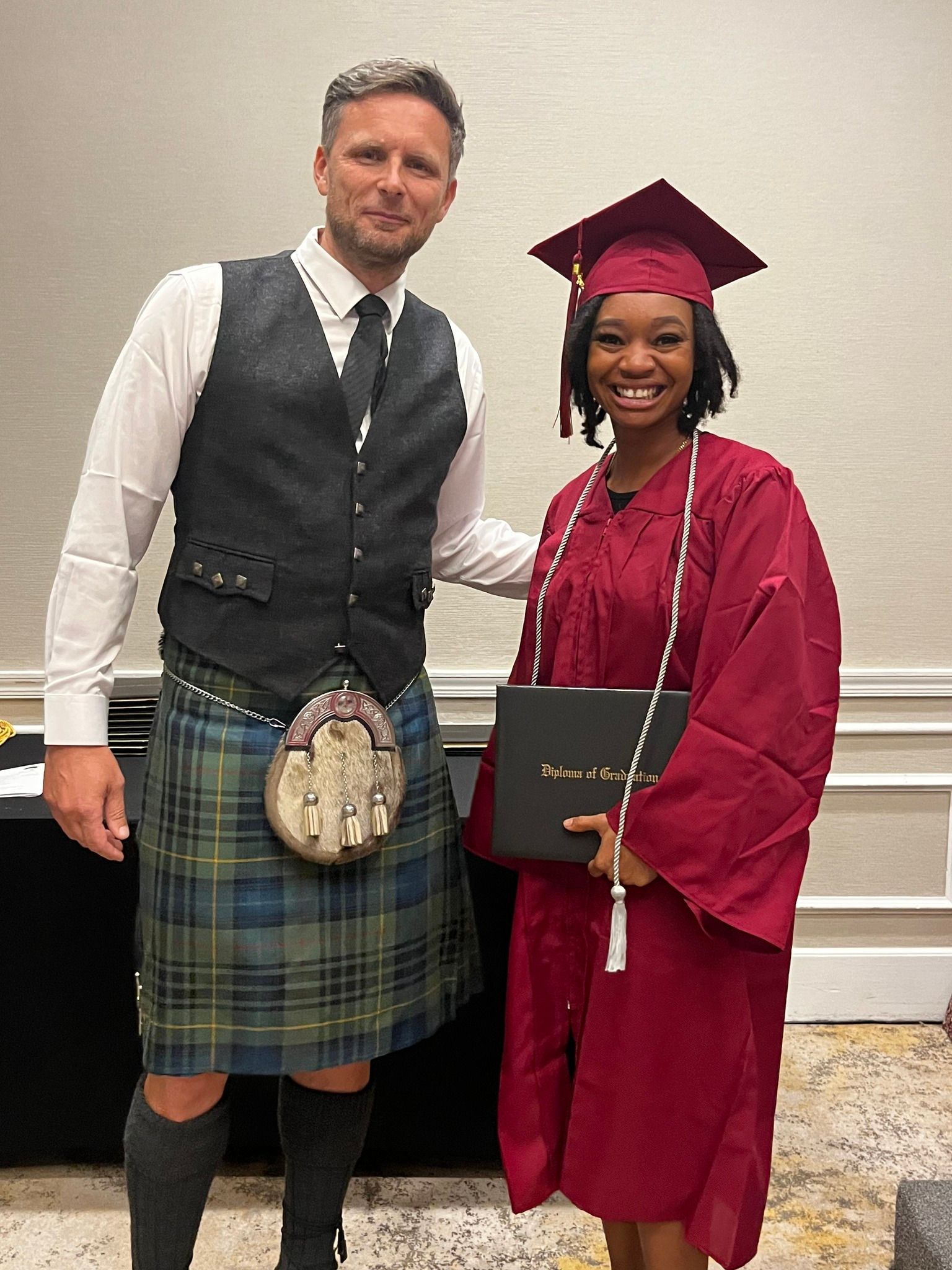 A man in a kilt is standing next to a woman in a graduation cap and gown.