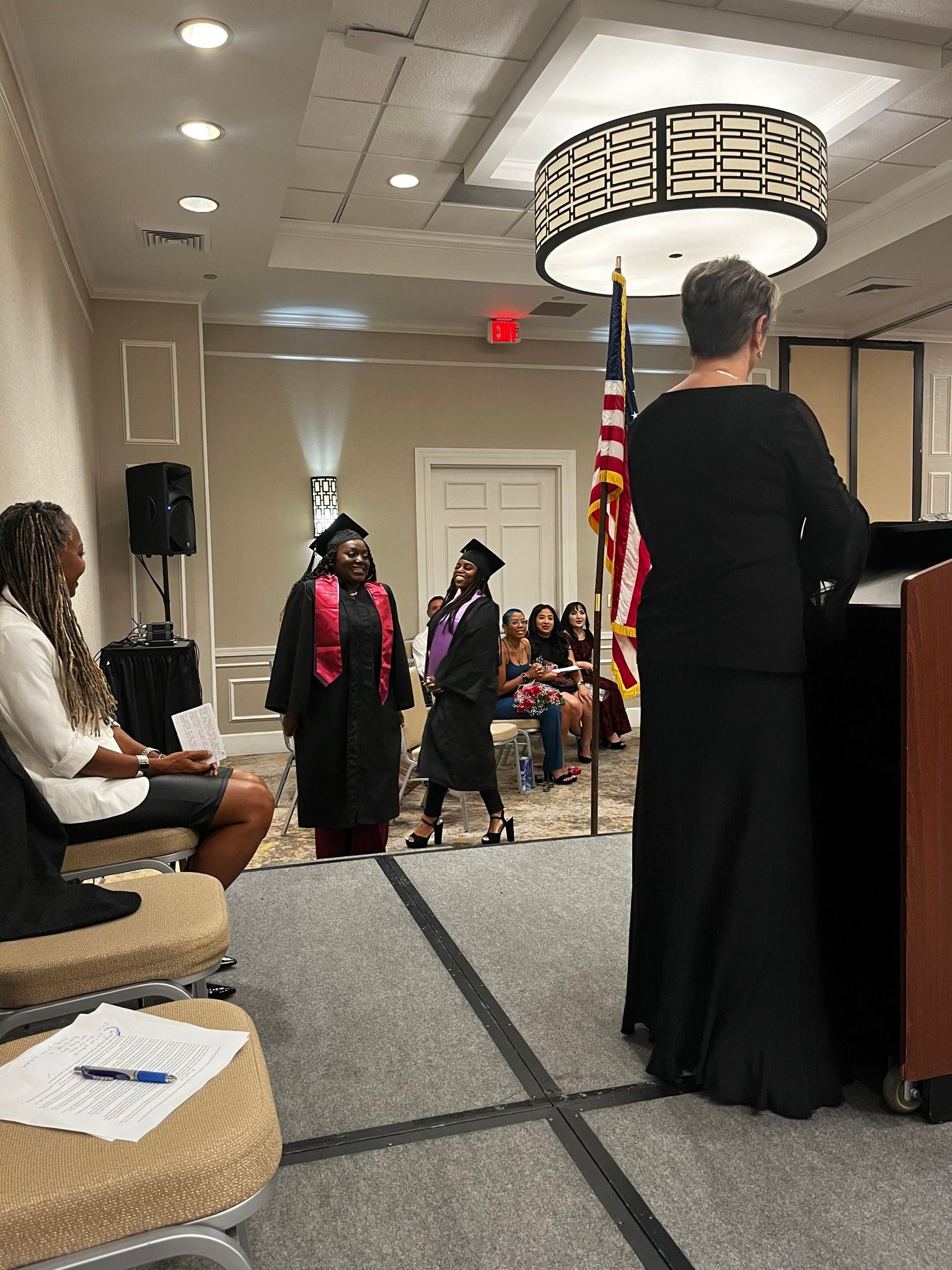 A woman is standing at a podium giving a speech at a graduation ceremony.