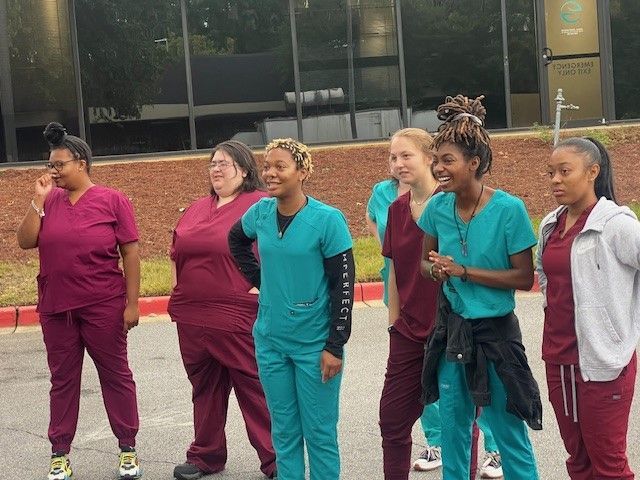 A group of nurses are standing next to each other in front of a building.