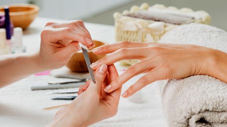 A woman is getting her nails done at a nail salon.