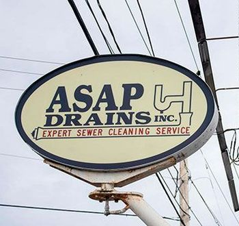 A sign for asap drains inc. hangs from a pole