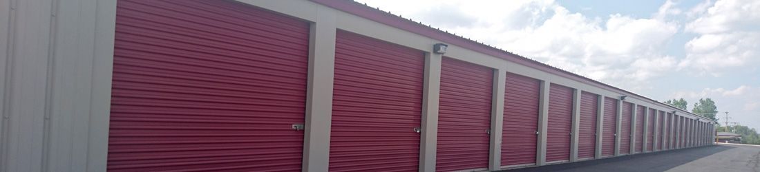 Red storage units with white trim, a gray roof, and a blue sky in the background.