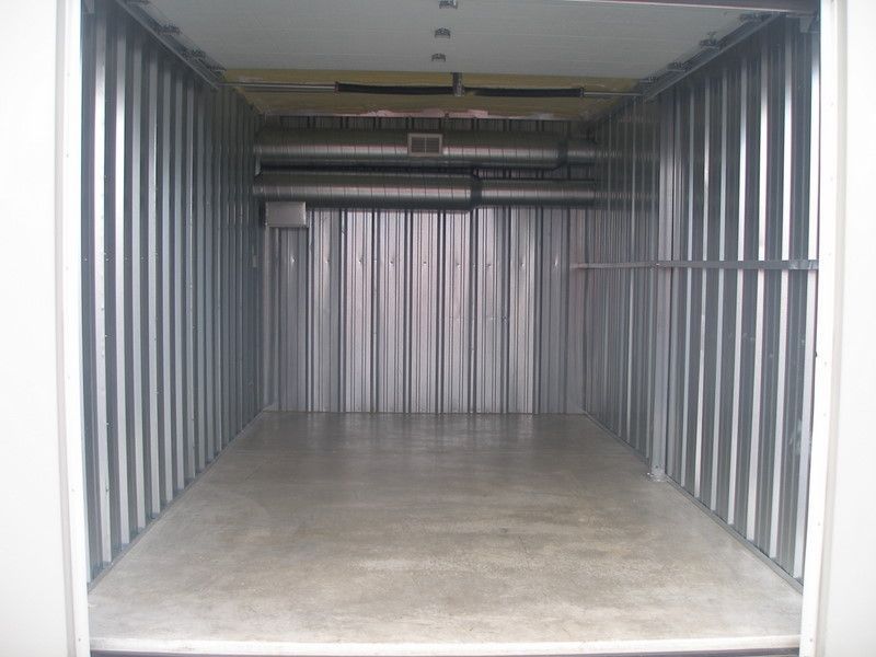Empty, metal storage unit with concrete floor and corrugated walls.