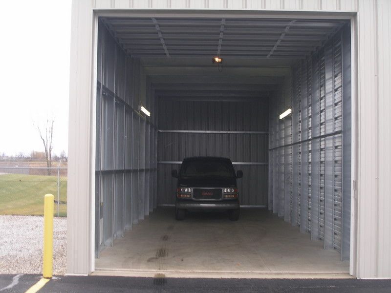 Inside of a metal storage unit with a black van parked in the center.