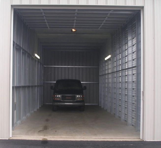 A black vehicle parked inside a metal storage unit with the door open.