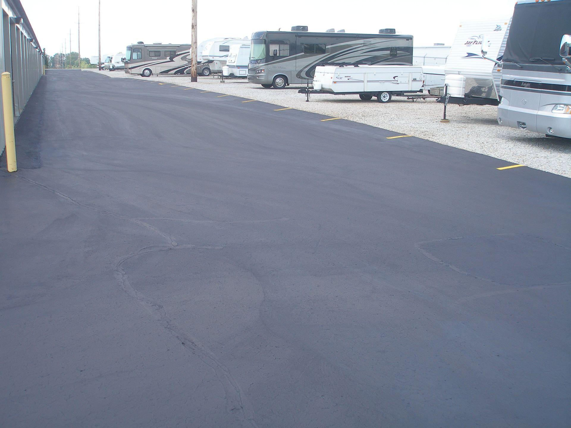 Asphalt road in RV storage lot. RVs parked on gravel.