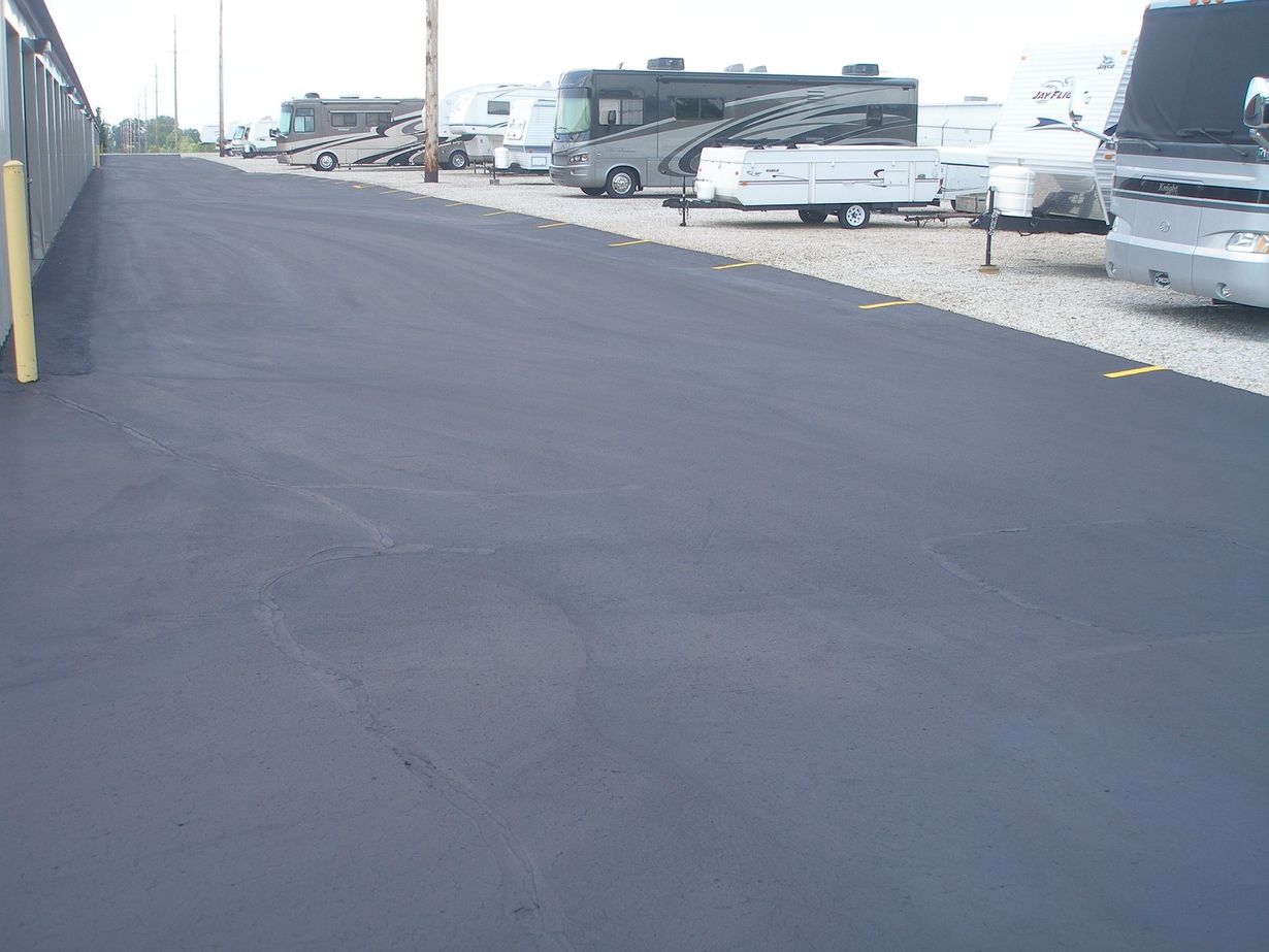Asphalt road with RVs parked on gravel.