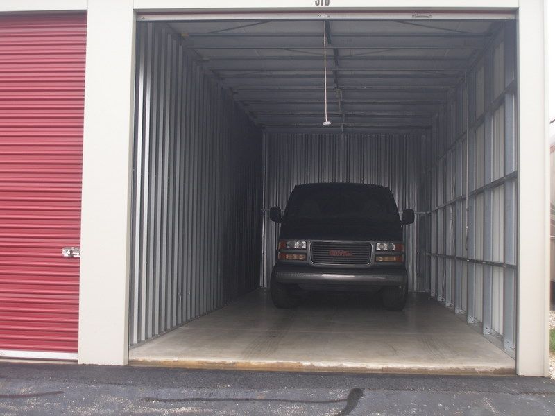 Van parked inside a storage unit with red door.