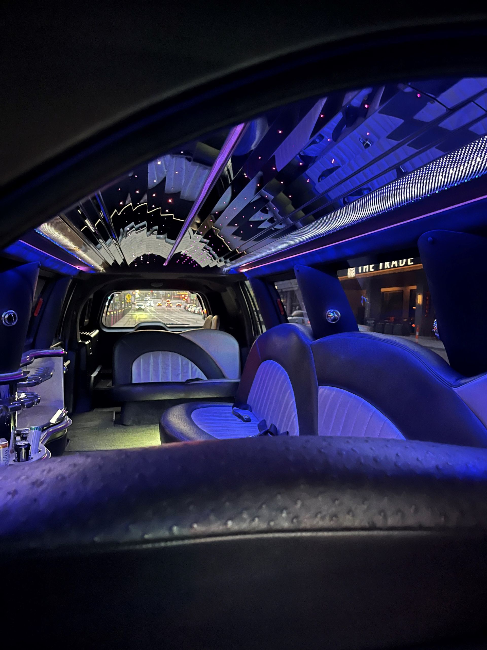 The inside of a limousine with blue lights on the ceiling.