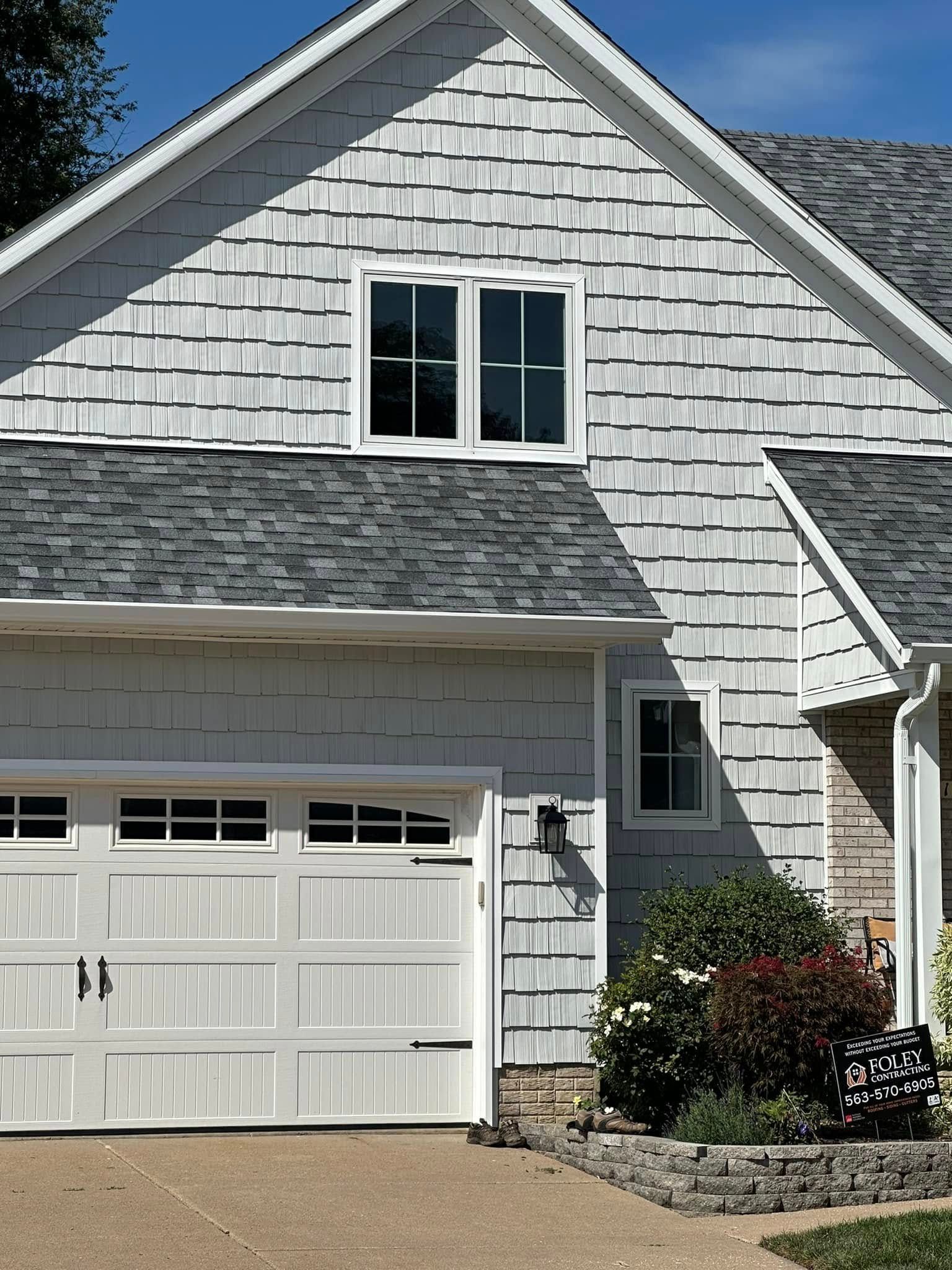A white house with a gray roof and a white garage door
