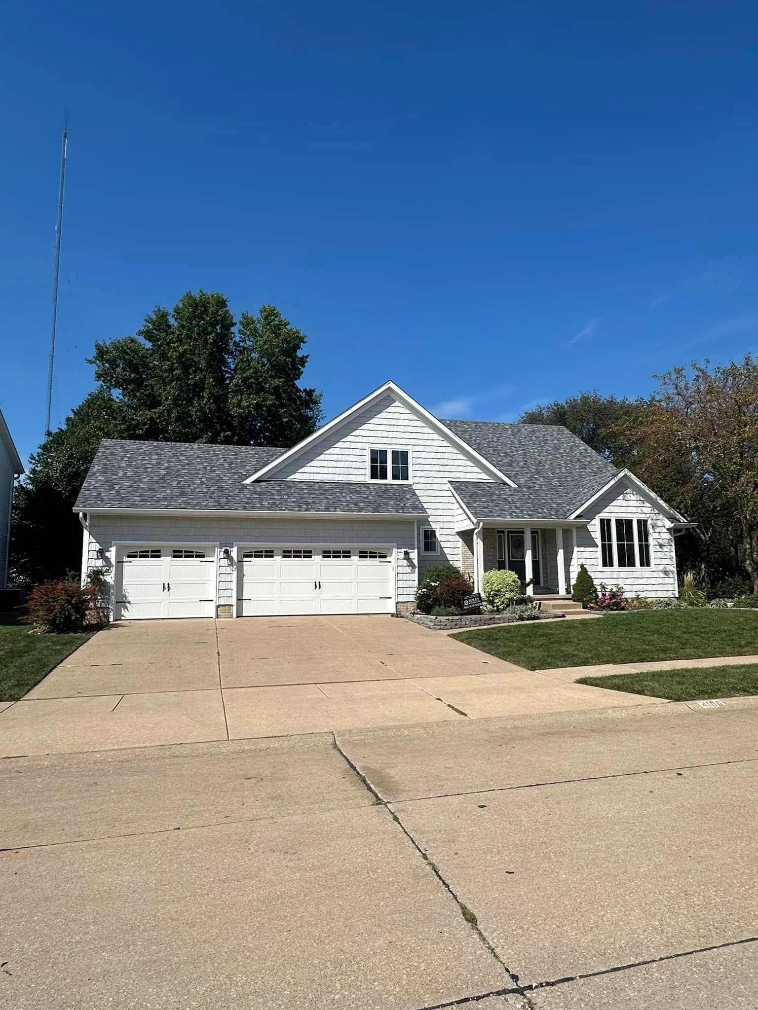 A white house with a gray roof and a driveway.