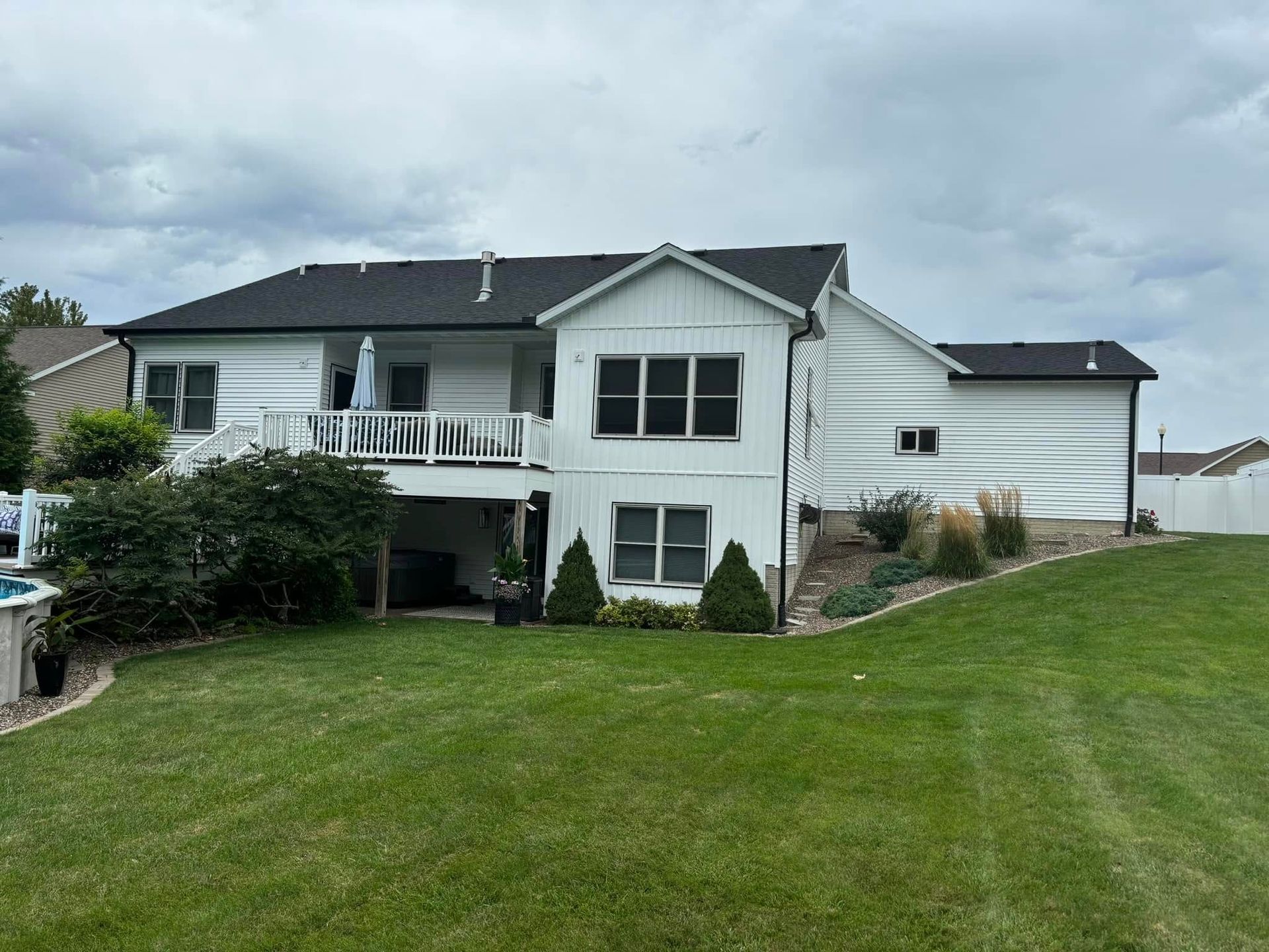 A large white house with a black roof and a large lawn in front of it.