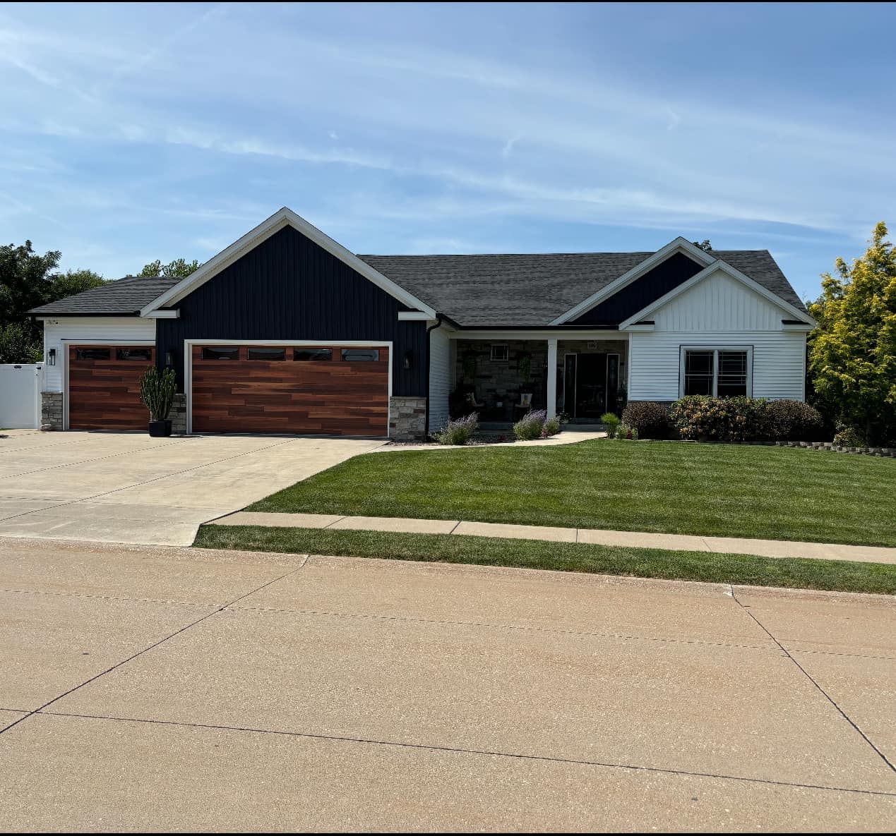 A large white house with a black roof and a wooden garage door.