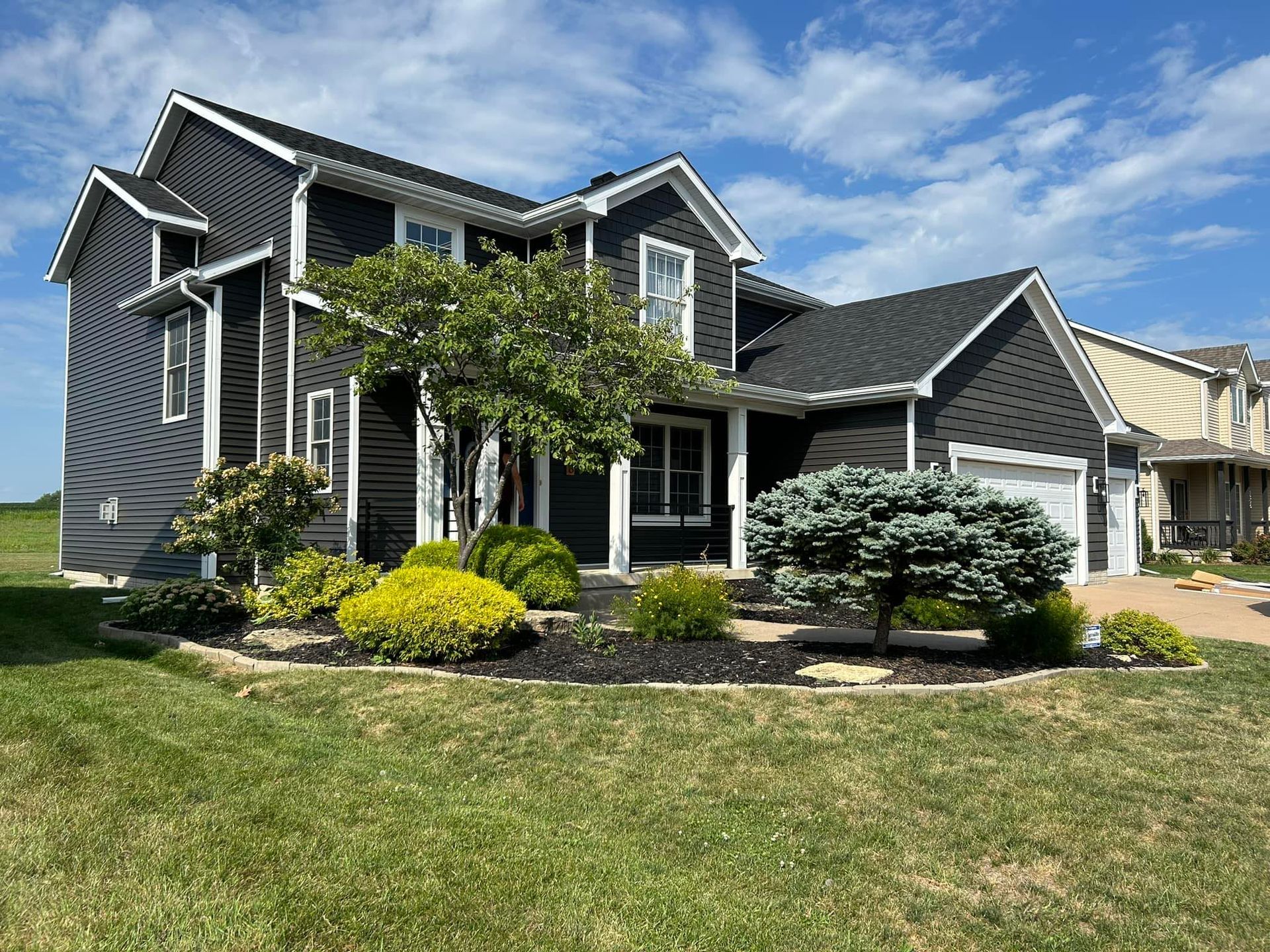 A large black and white house with a large lawn in front of it.