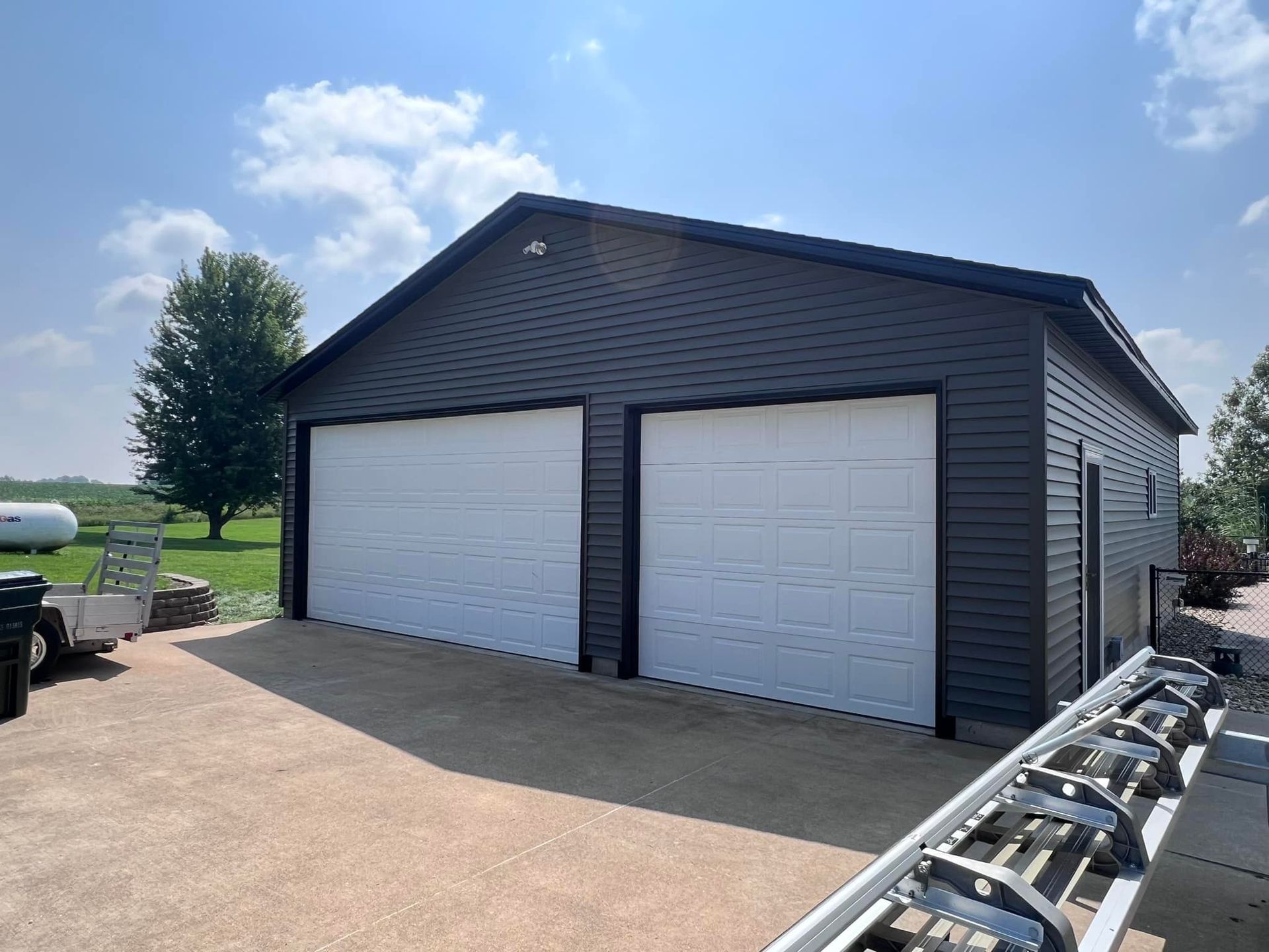 A black garage with two white garage doors and a truck parked in front of it.