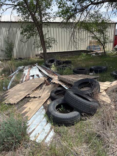 A pile of tires and cardboard is sitting in the grass in front of a building.