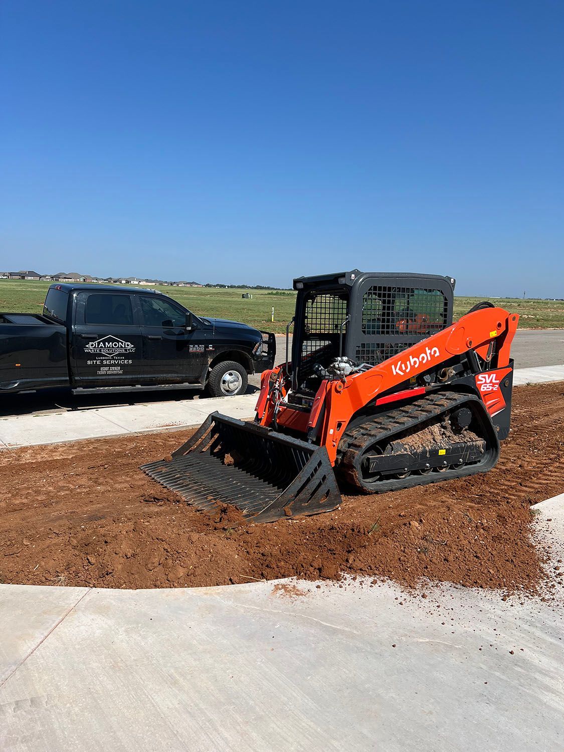 A skid steer compacting and smoothing dirt.