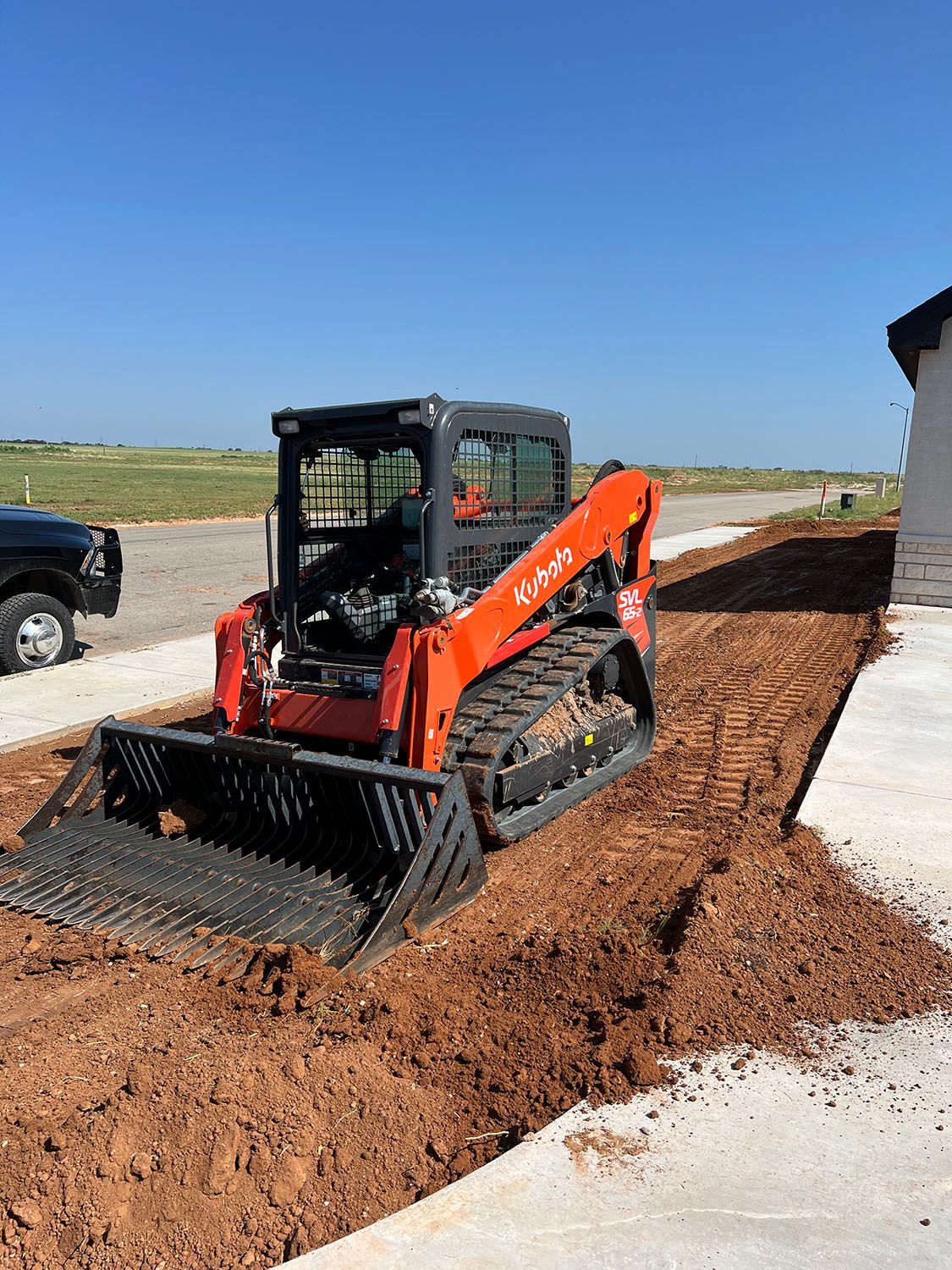 A skid steer compacting and smoothing dirt.