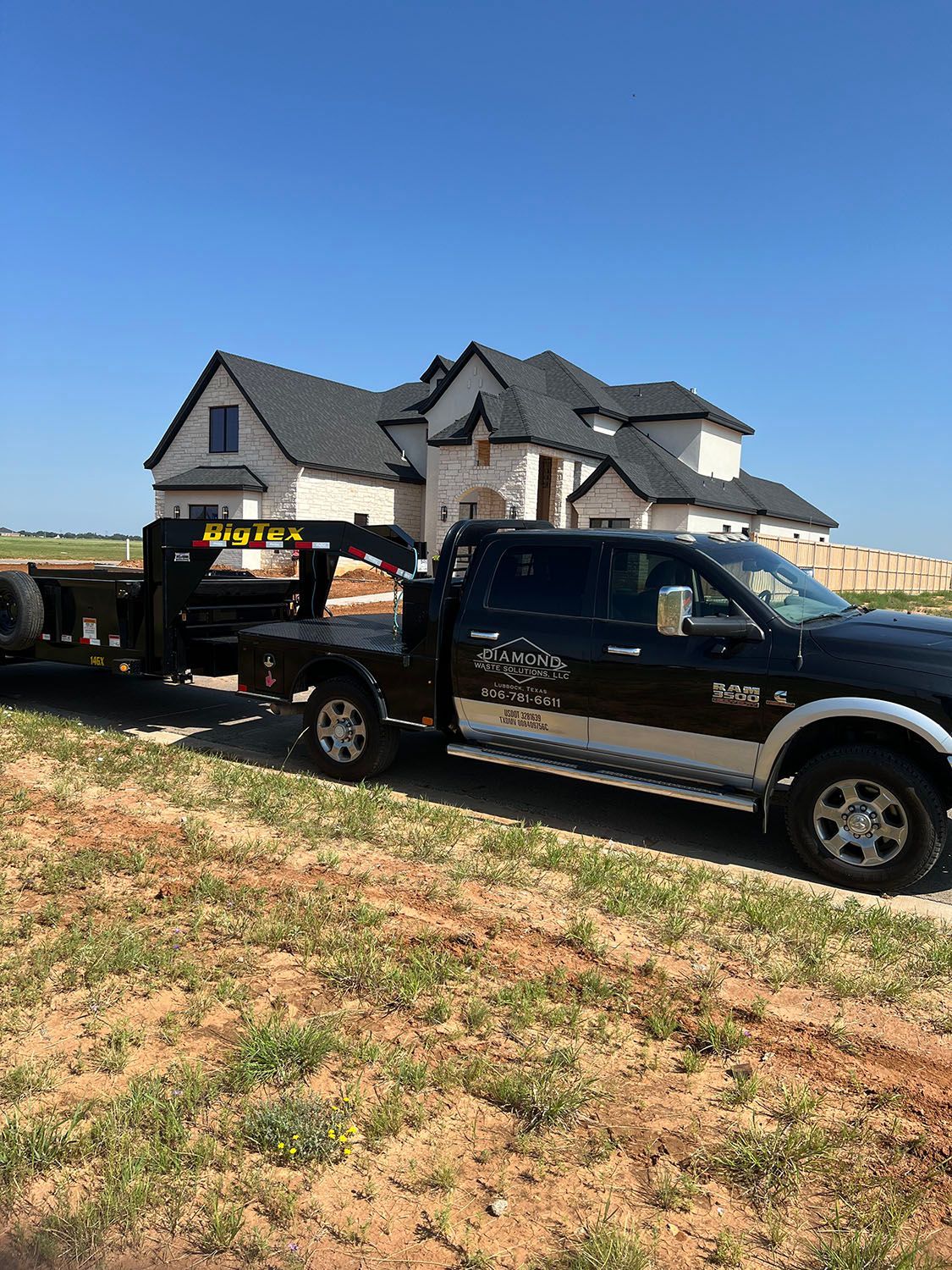 Black pickup truck with trailer parked in front of a large white house.