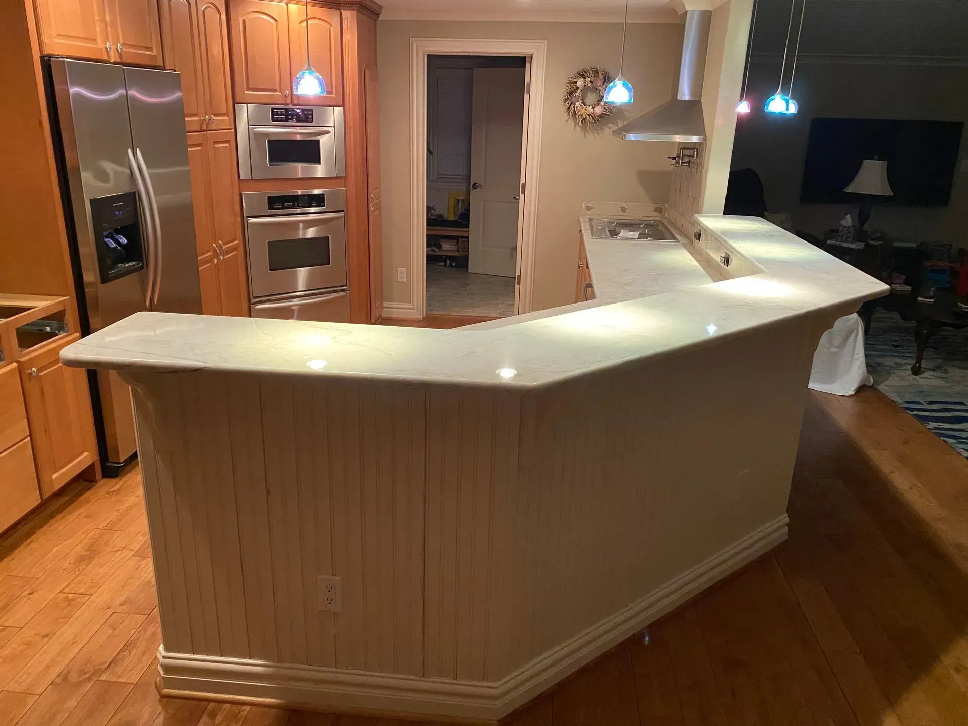 Kitchen with light wood cabinets, stainless steel appliances, and a white countertop island.