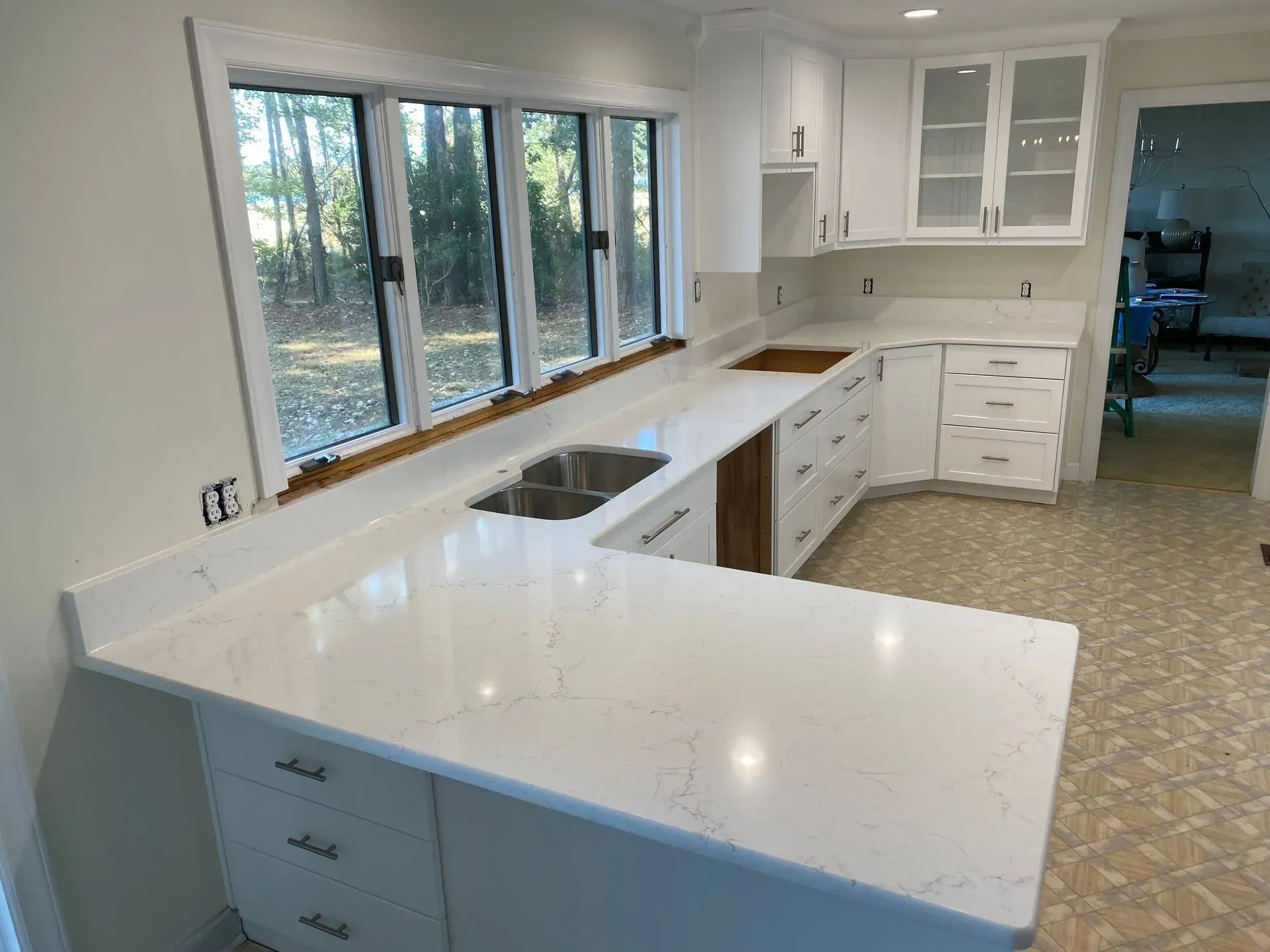White kitchen with quartz countertops and a window over a double sink.