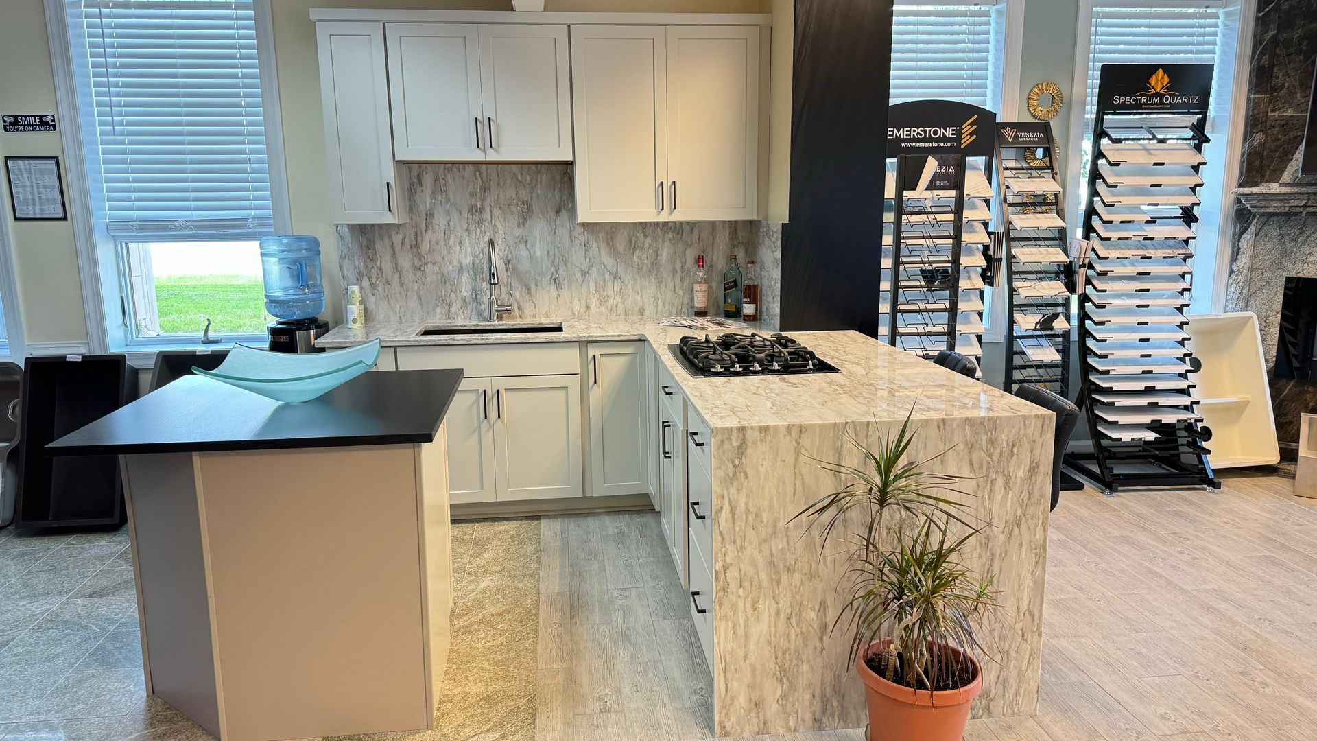 Kitchen with white cabinets, granite countertops, and an island. A water cooler and stone samples are visible.