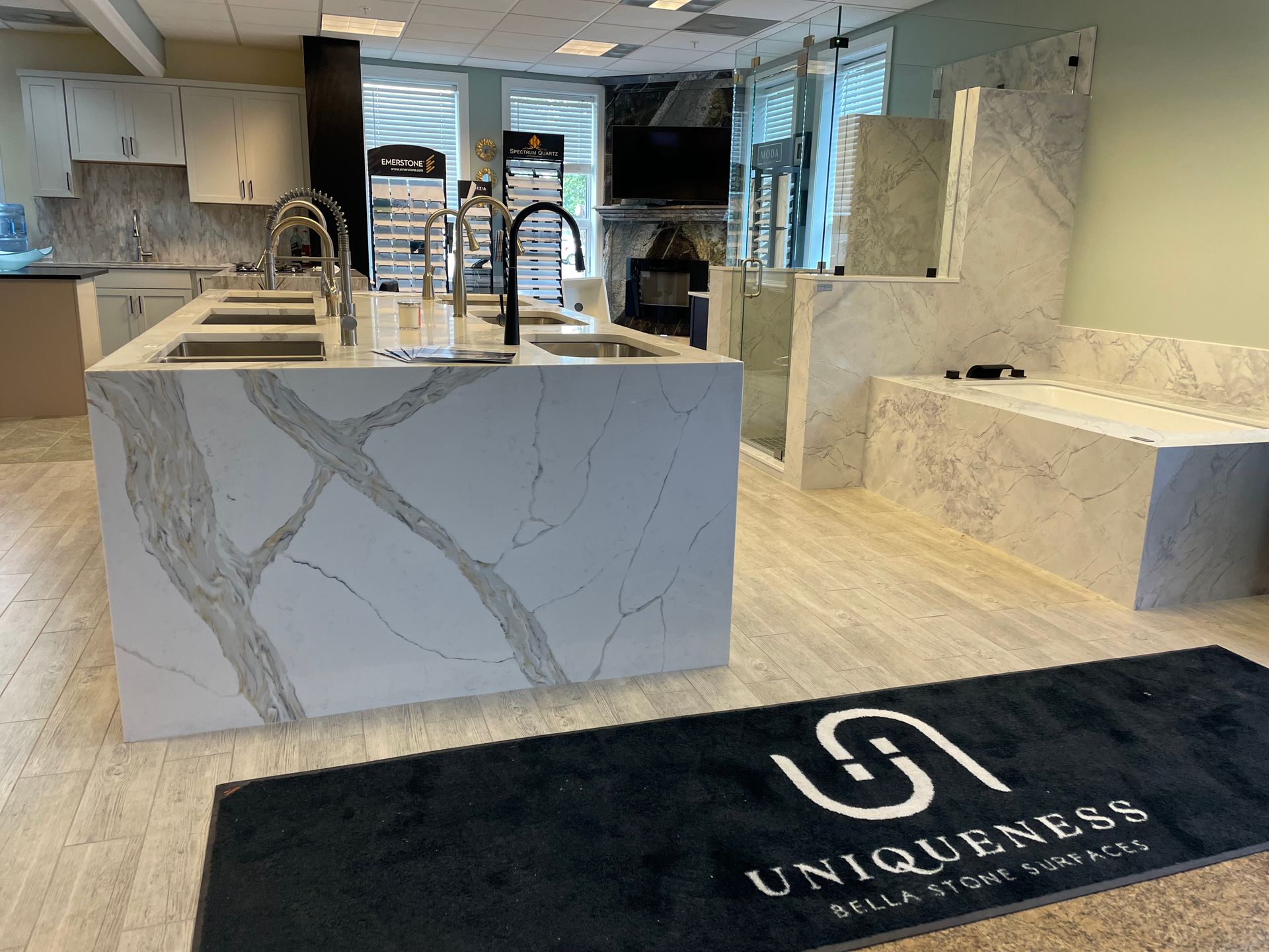 Kitchen showroom featuring stone countertops and fixtures; a black 