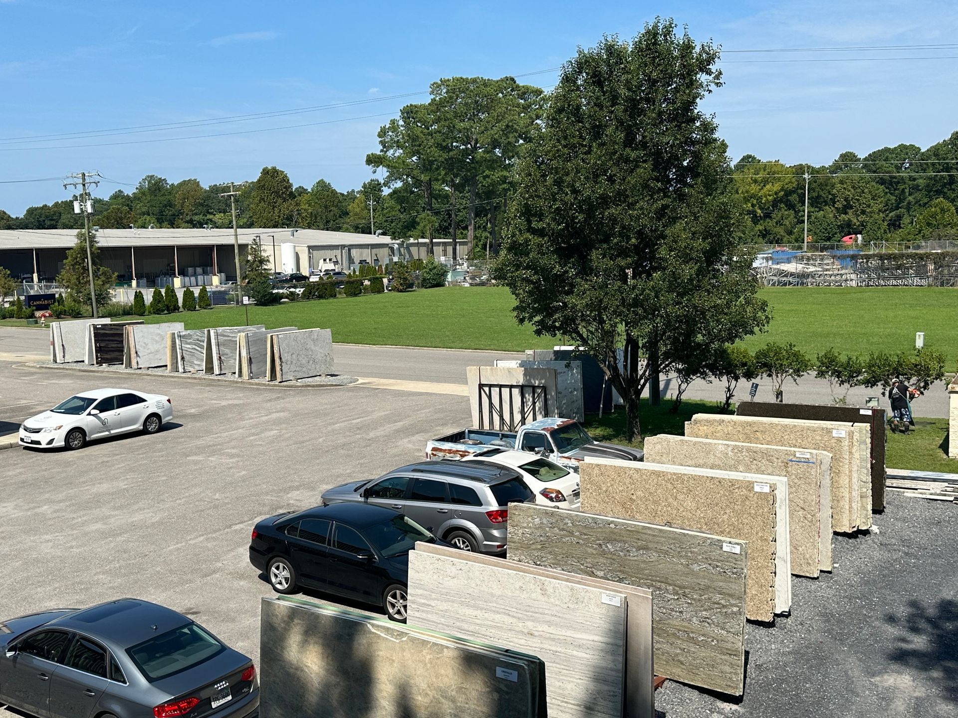 Stone slabs displayed outside a building with parked cars on a sunny day.