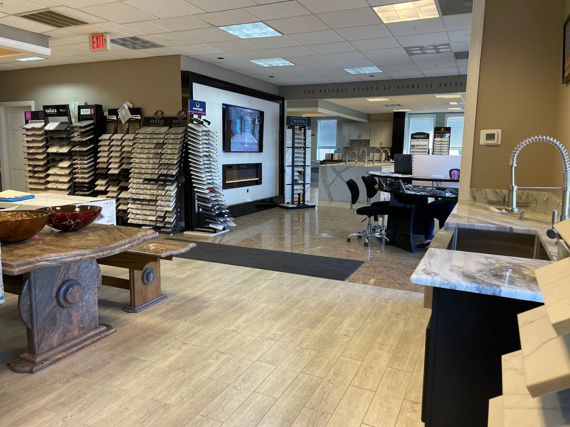 Showroom with tile and stone displays, including a fireplace and kitchen sink.