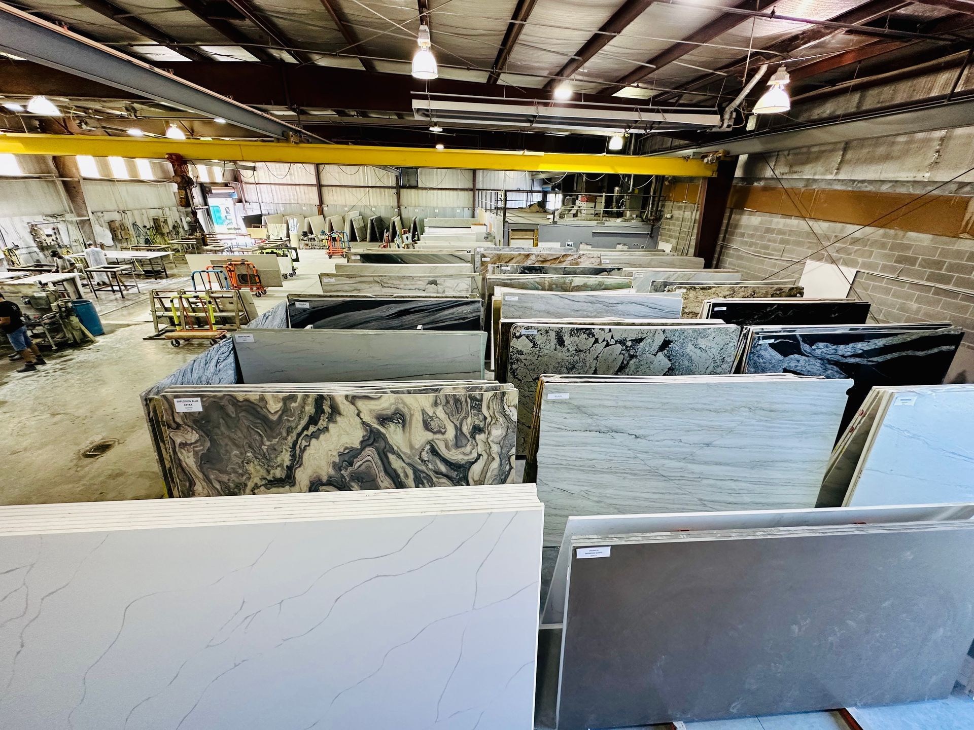 Warehouse with rows of stone slabs; overhead crane visible.