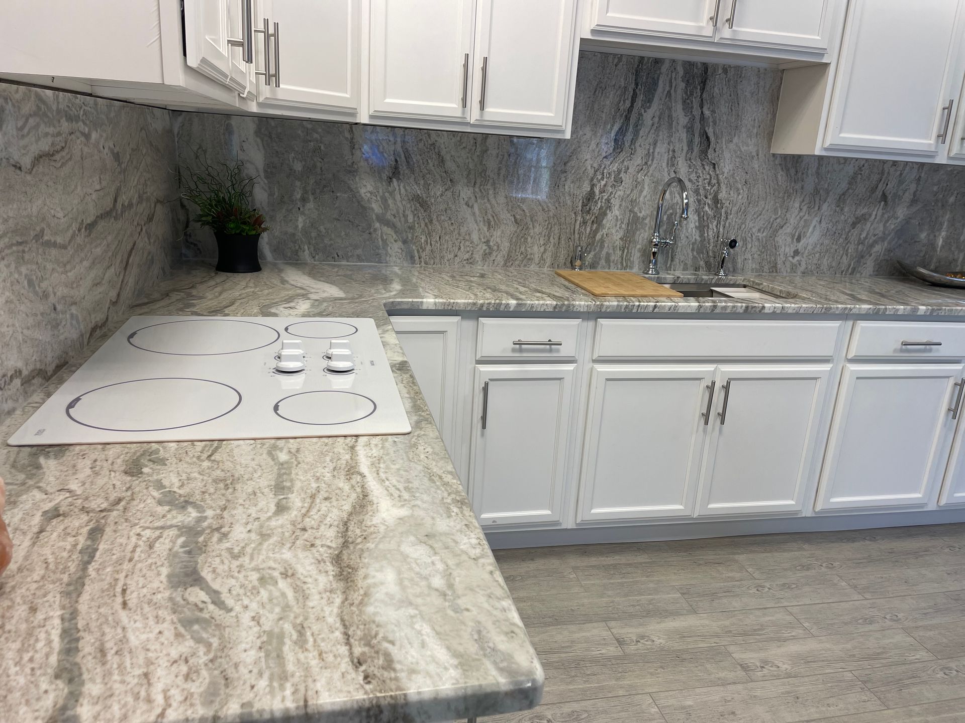 White kitchen with granite countertops, stovetop, and cabinets.
