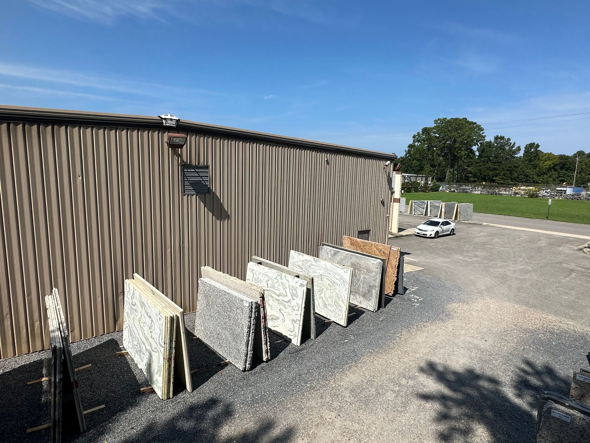 Stone slabs displayed outside a corrugated metal building on a sunny day.