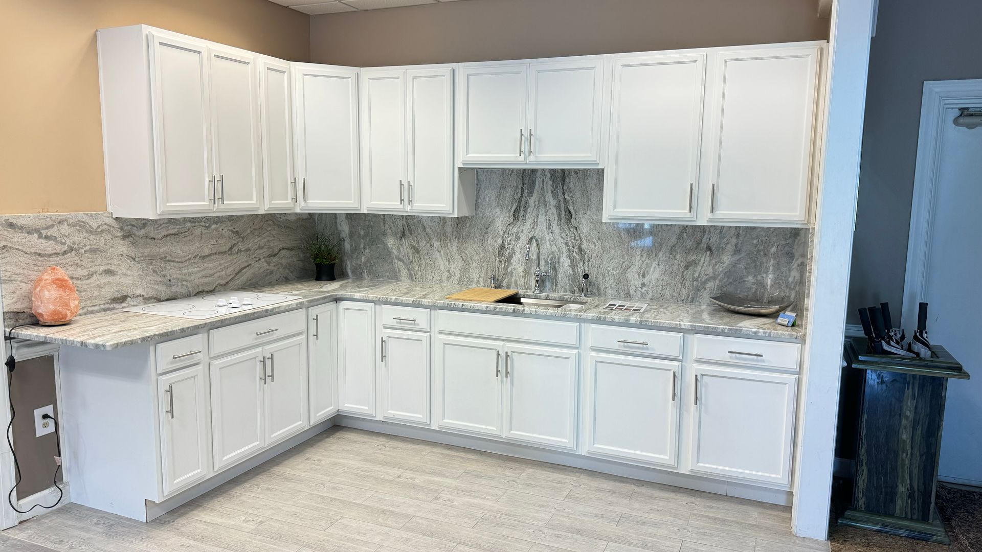 White kitchen cabinets with granite countertops and backsplash.