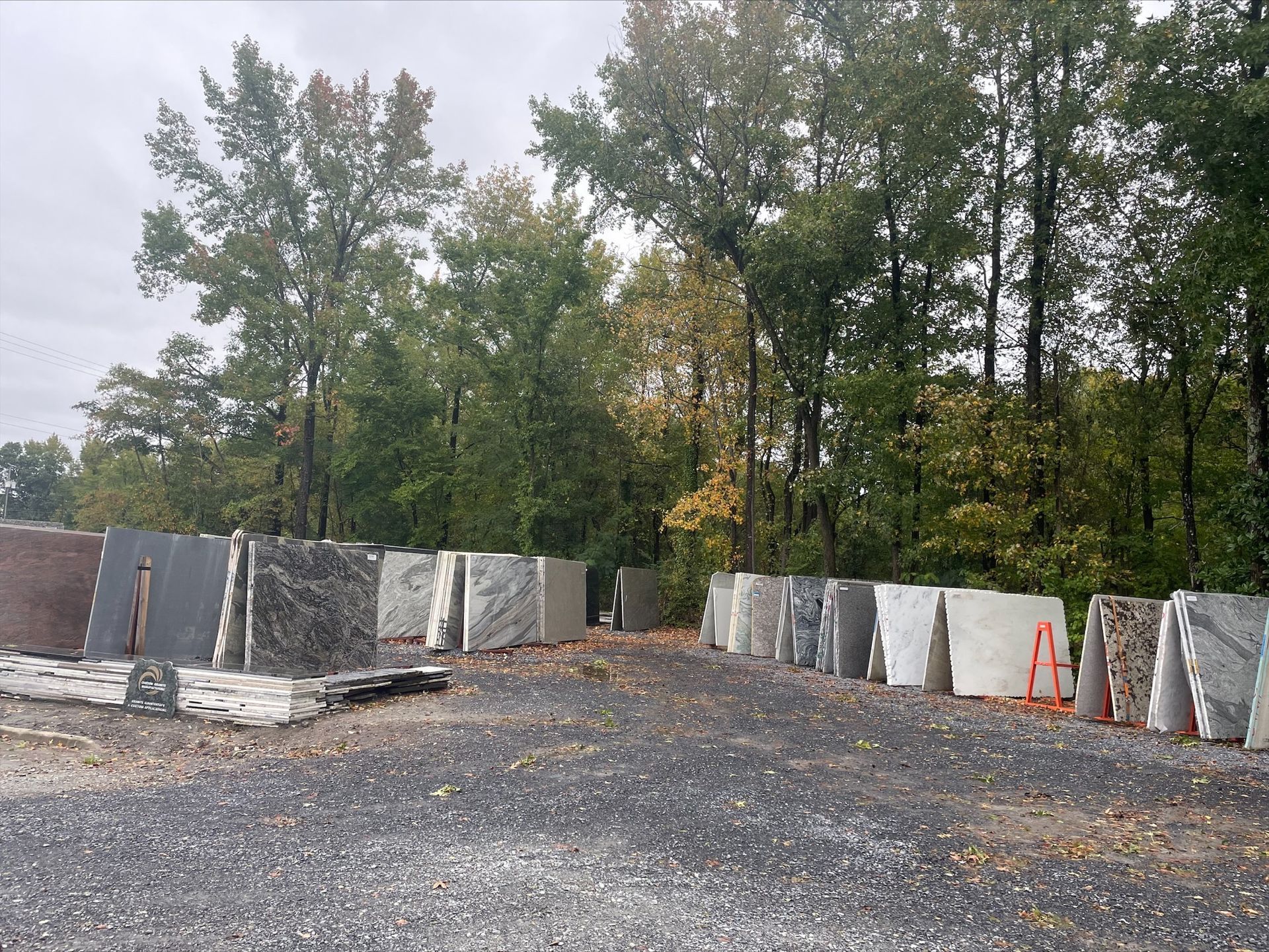 Slabs of stone displayed outdoors against a backdrop of trees, likely for sale.