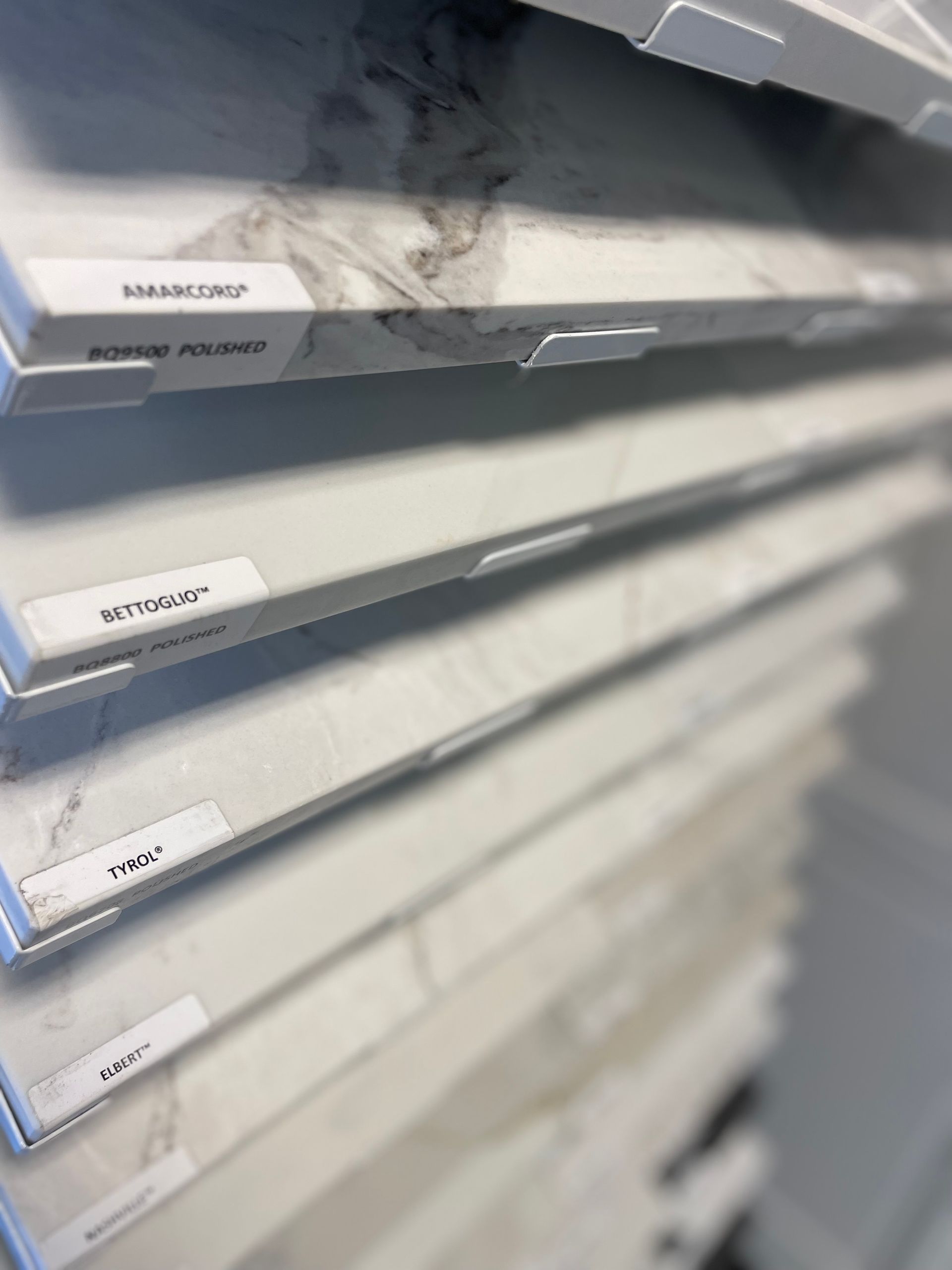 Samples of countertop materials on display. White and gray variations, labeled.