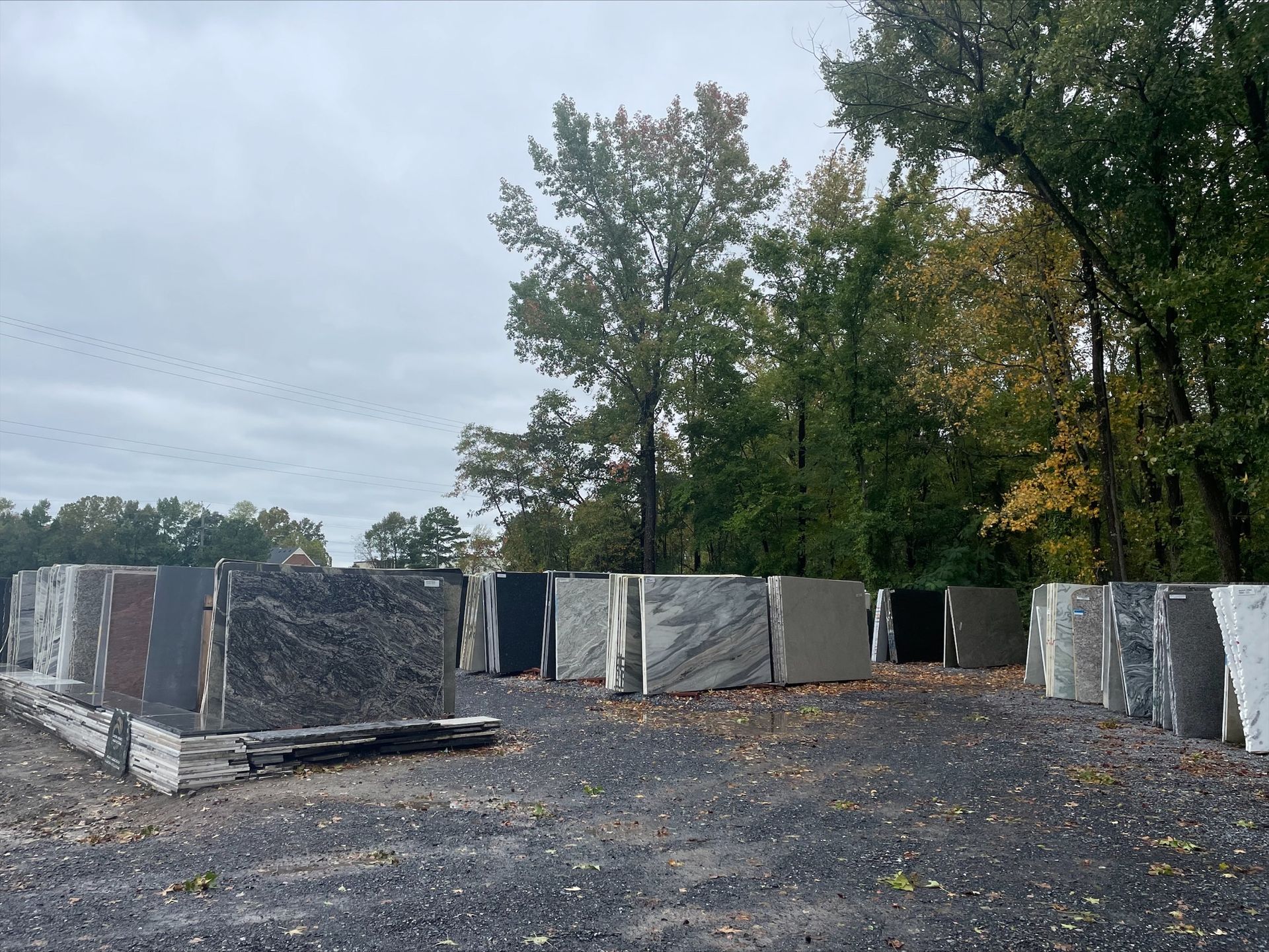 Stone slabs displayed outdoors against a backdrop of trees under an overcast sky.